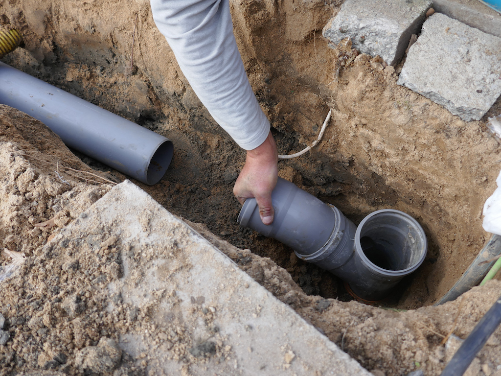 Man working on sewer line repair PVC pipe. 