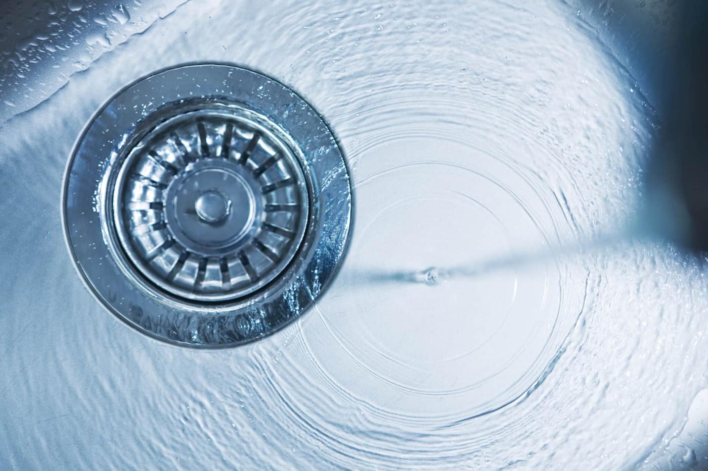 Close-up of a kitchen sink with water running away, Drain Cleaning.