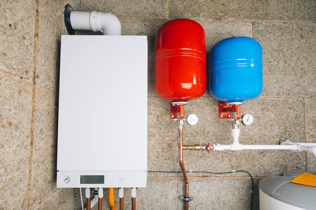 Red and blue expansion tanks for water heater in boiler room.