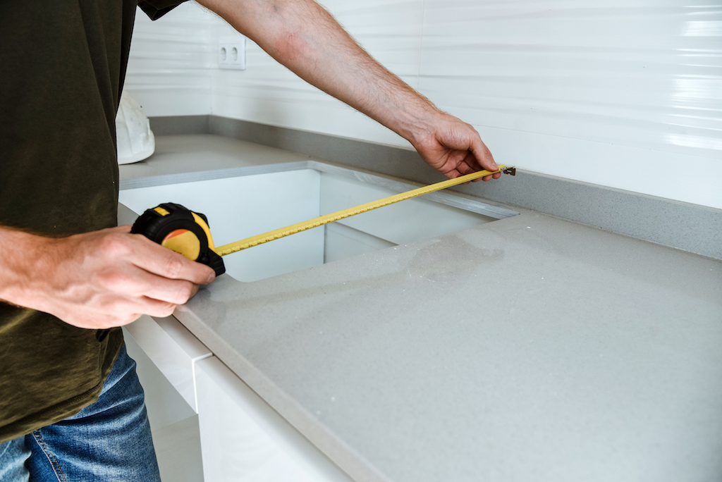 Detail of a man measuring the gap in a bathroom countertop. Bathroom sink replacement 