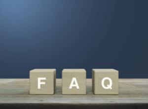 Blue background with wooden blocks that reads FAQ, representing questions about tankless water heater repair.