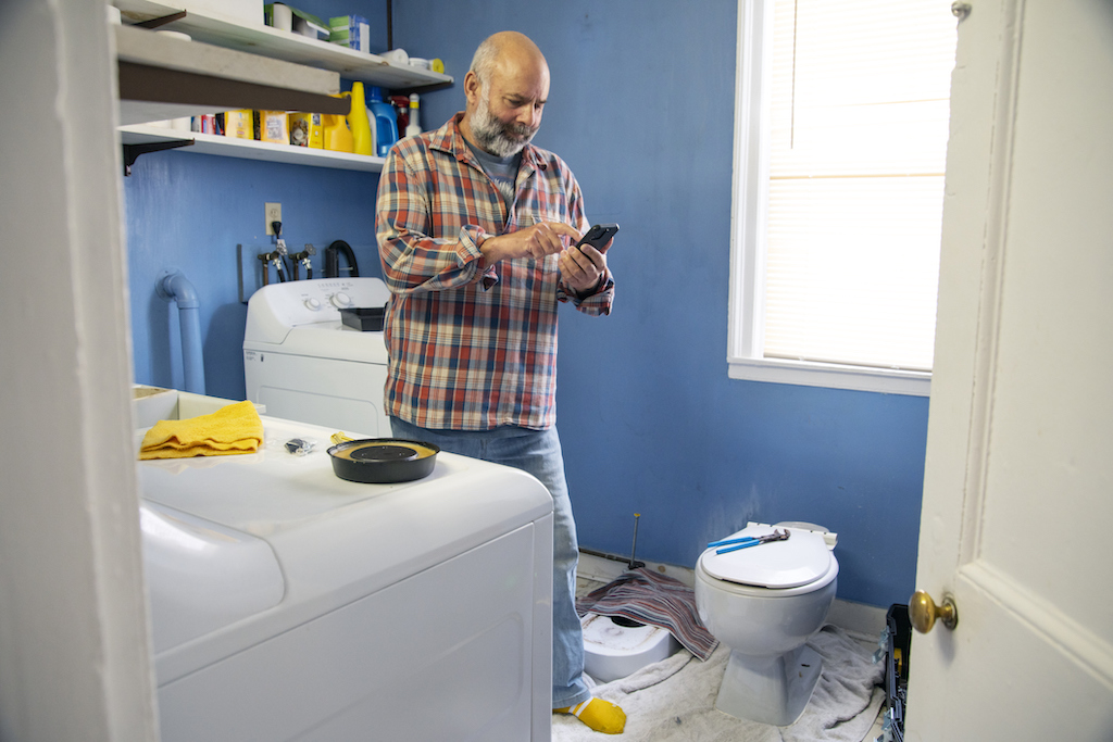 A man giving up his DIY journey to call a professional for tankless water heater repair.