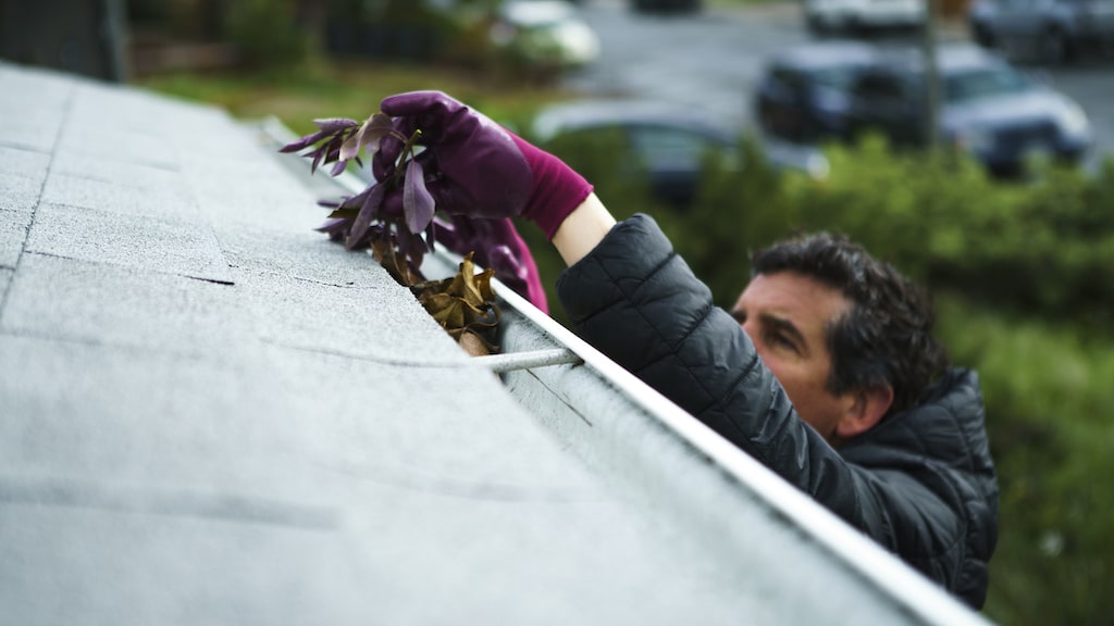 DIY roof drain cleaning man with red gloves.