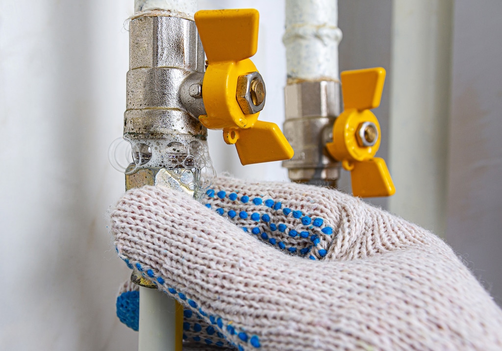 Man with gloves checking gas line for Gas Leak Detection and Repair. 