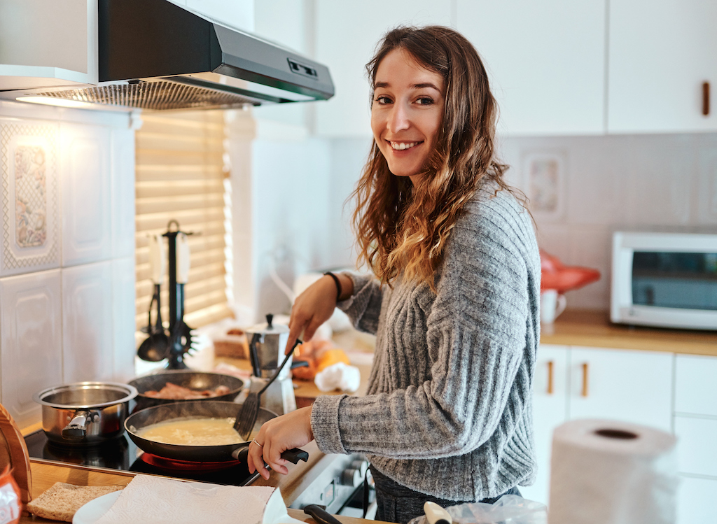 Happy woman cooking on stove. | Leak Detection and Repair
