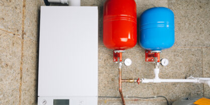 Red and blue expansion tanks for water heater in boiler room.