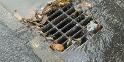 Clogged storm drain on residential street. | Storm Drain Cleaning Service