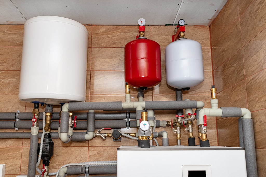 Red and white expansion tanks for water heaters in basement.