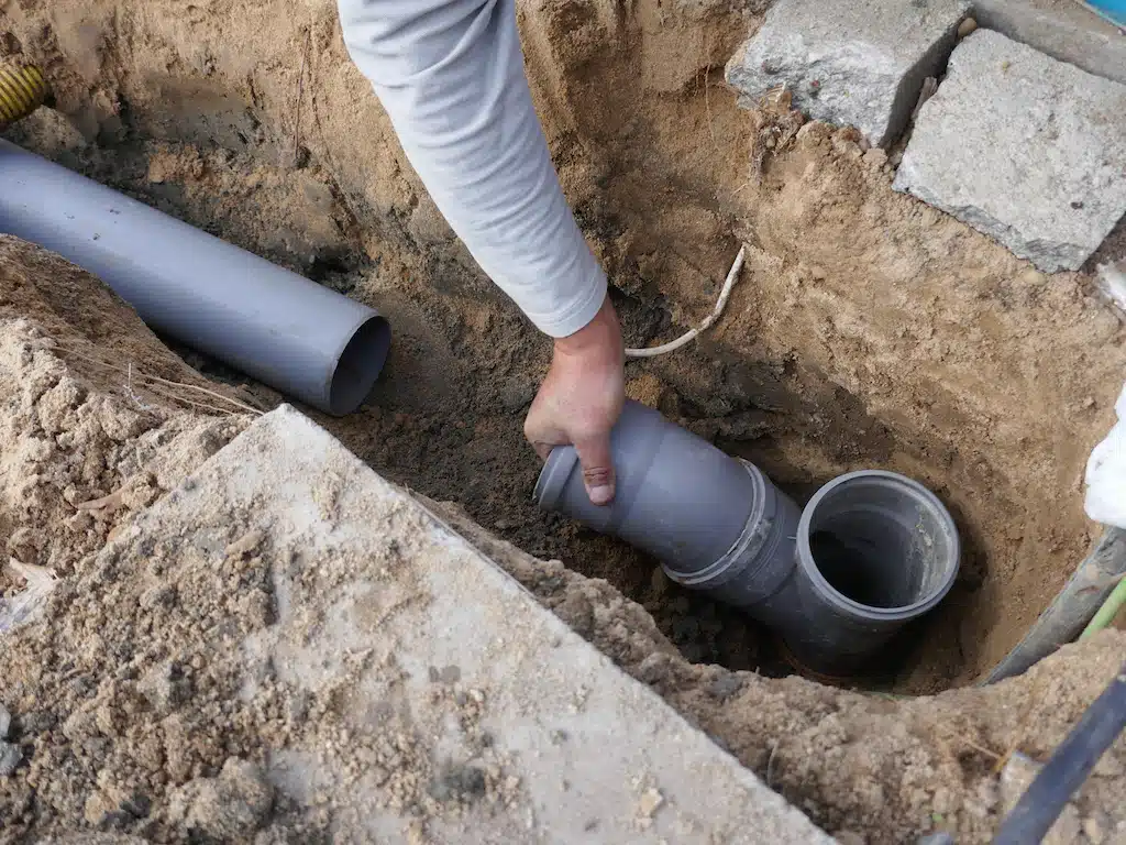 Man working on sewer line repair PVC pipe.