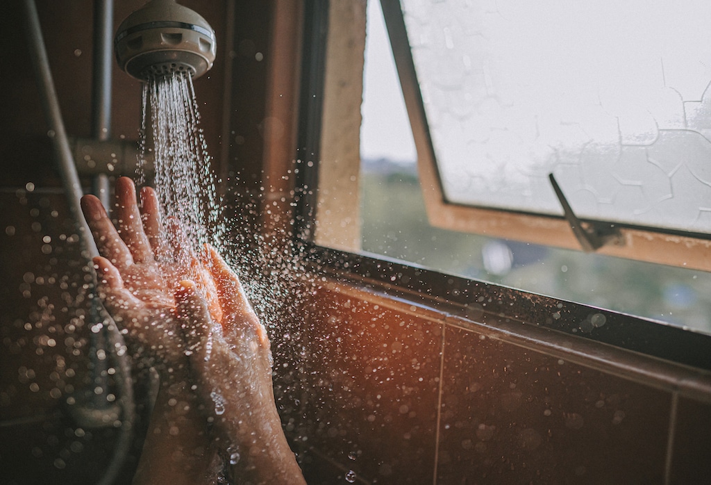 Hands checking water temperature on shower heads.