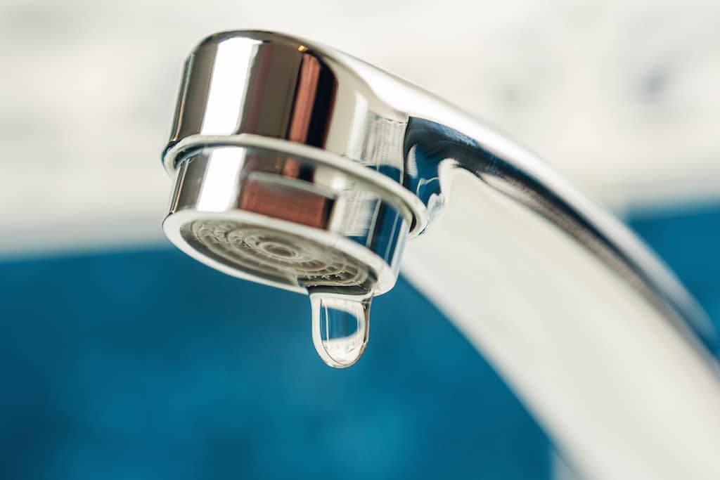 Water faucet with drip coming from sink. 