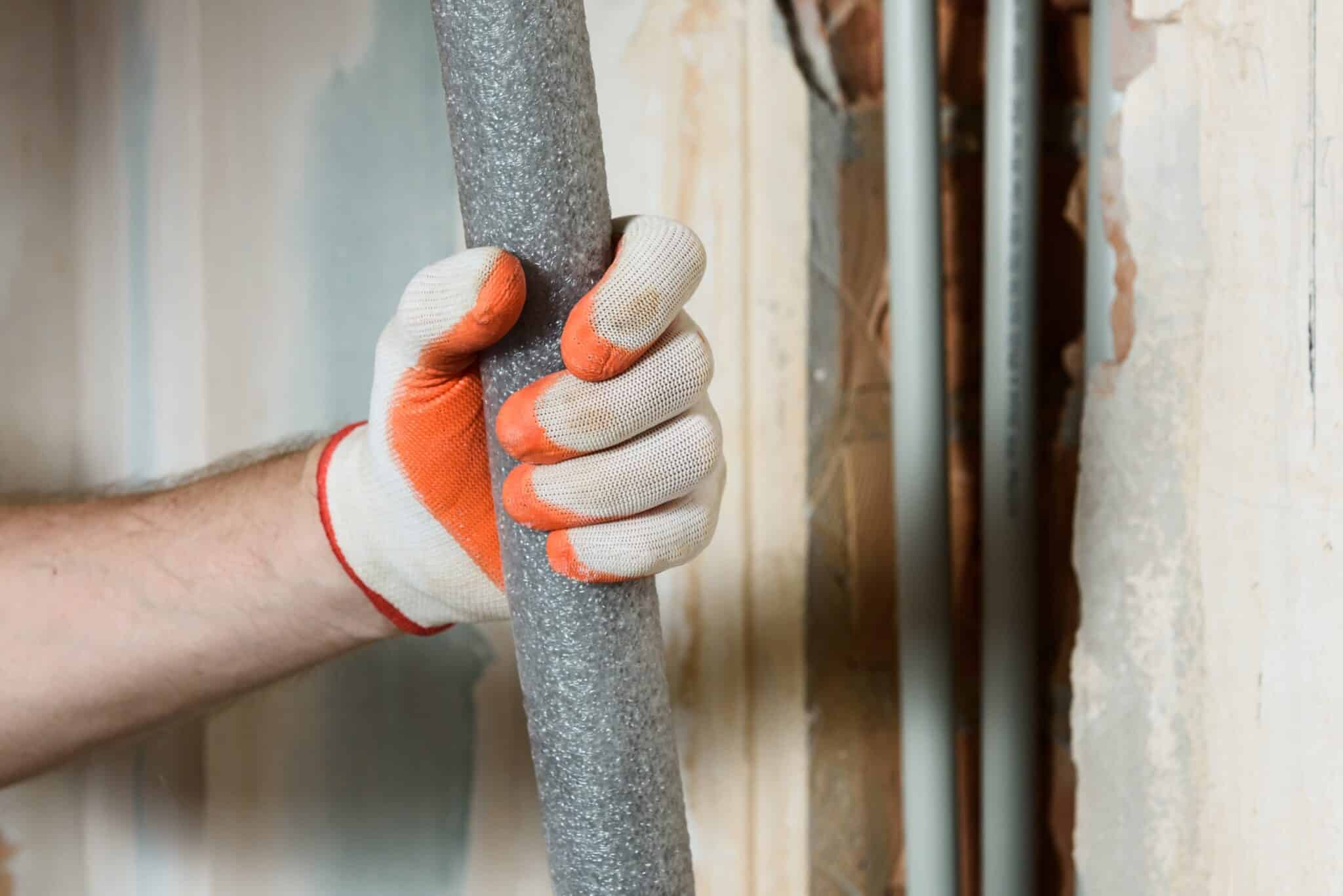 A plumber's hand is holding insulation for home heating pipes, Pipe Inspections.