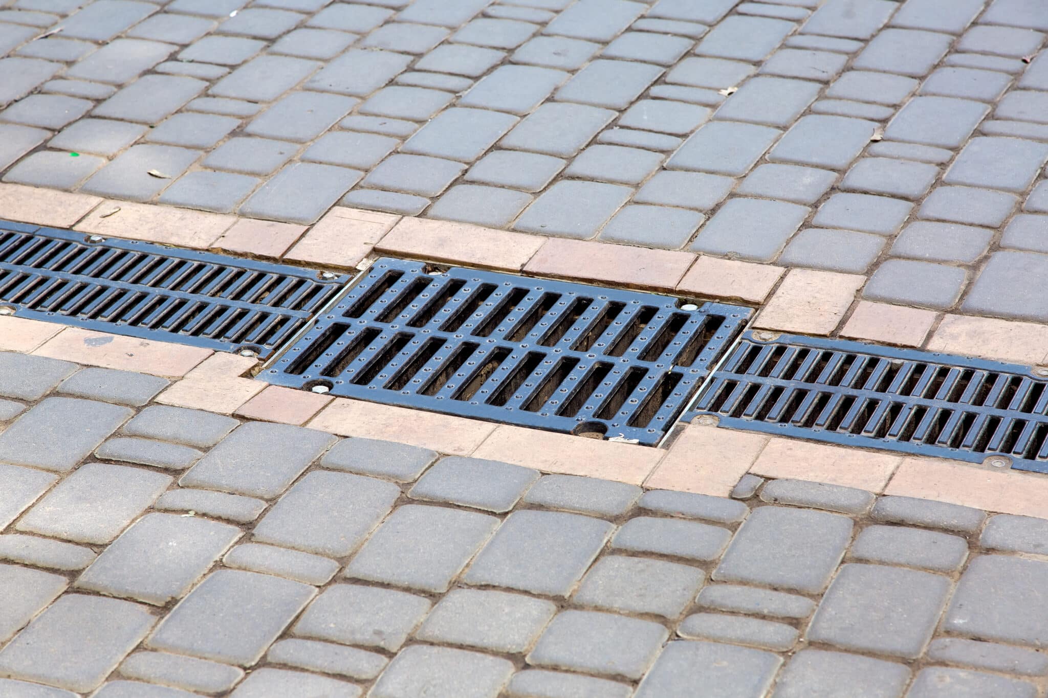 A lattice of a drainage paving system on a path made of square stone tiles, Drain Cleaning.
