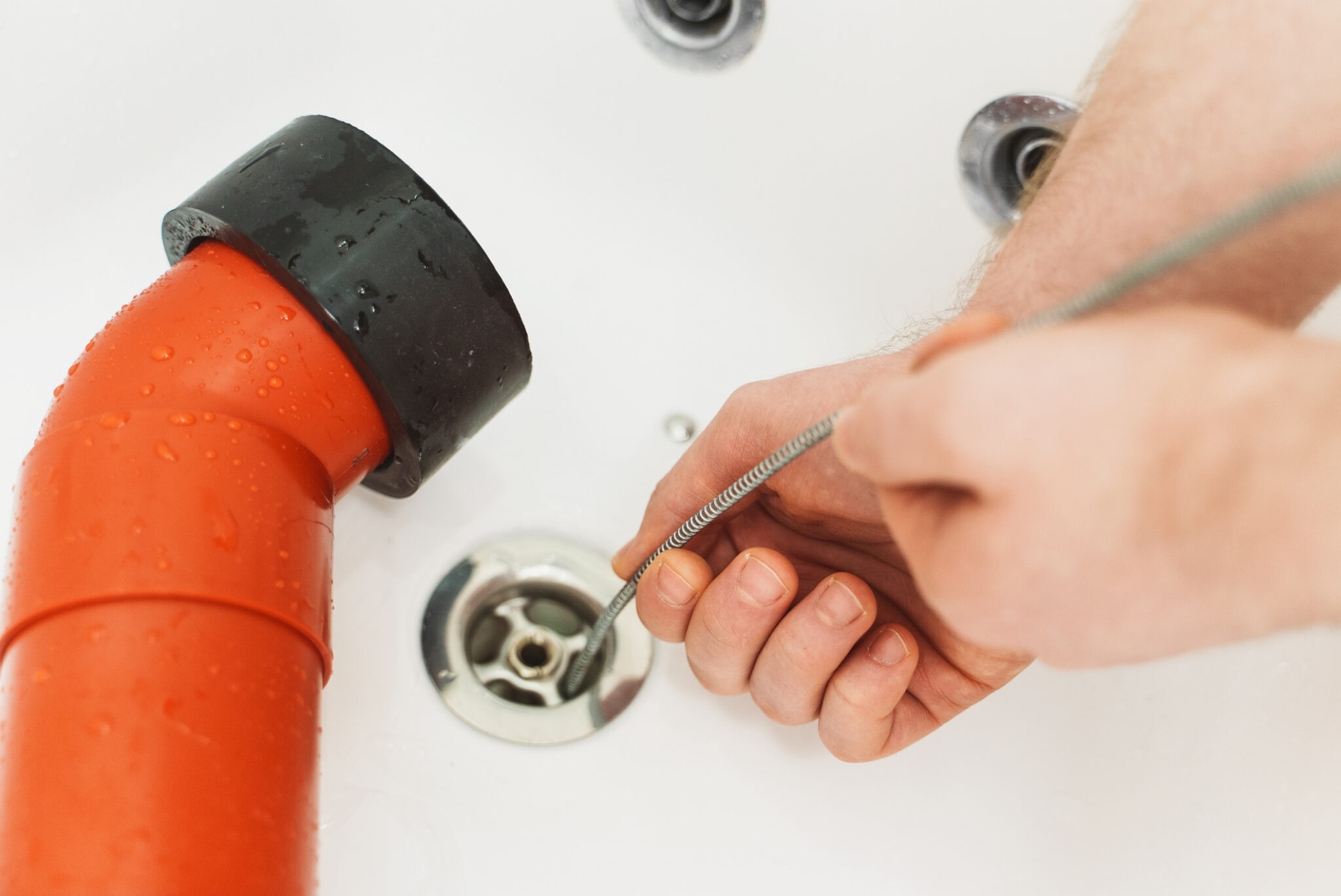 Professional drain unclogging service using a drain snake to remove blockages.